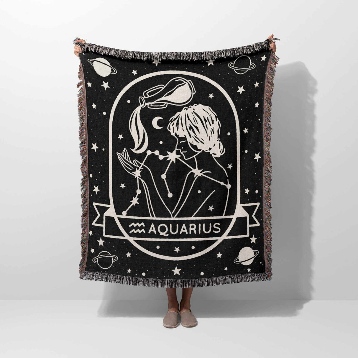 This image features a person holding a Zodiac Sign Blanket vertically, displaying the Aquarius astrological sign. The woven throw tapestry showcases a detailed black-and-white design with celestial and constellation elements, perfect for astrology enthusiasts and home decor.